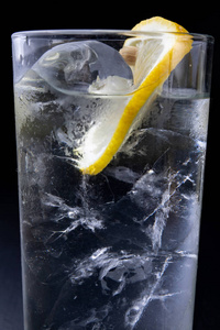厨房桌子上的玻璃杯里的冷饮。 柠檬和冰加水是夏天凉快的最好方法。 黑暗的背景。
