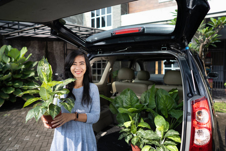 妇女与植物和树木在她的汽车后备箱