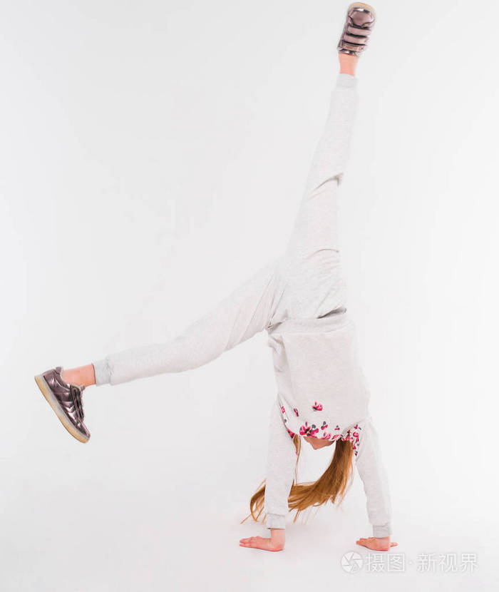 活跃的小女孩在白色的背景下做一个手倒立
