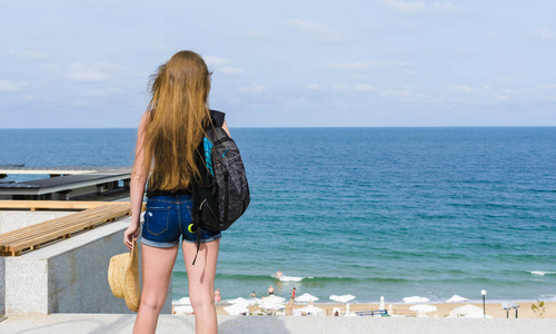 女孩游客看在海滩和大海