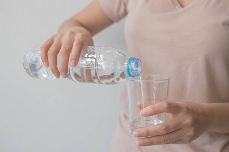 s hand holding a bottle of water Pouring water into a glass