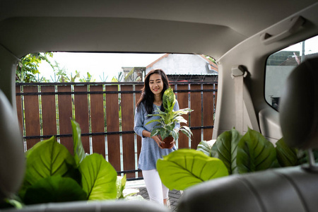 妇女与植物和树木在她的汽车后备箱