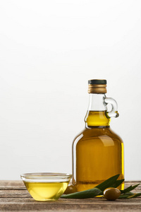 碗和瓶油，橄榄树叶和橄榄隔离在灰色
