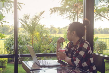 一位年轻的亚洲妇女在用笔记本电脑工作后独自坐在咖啡店里放松