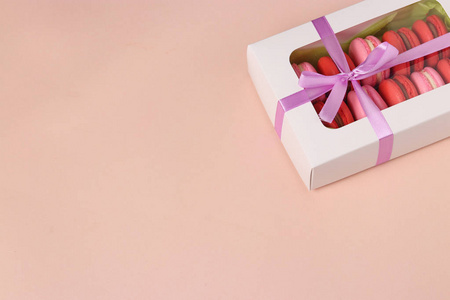 美味的甜饼干，通心粉，在一个白色的礼品盒上，粉红色的背景，红色和粉红色的通心粉。 复制空间