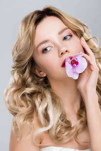 年轻优雅迷人的女人，嘴里叼着紫色的兰花，嘴里隔着灰色