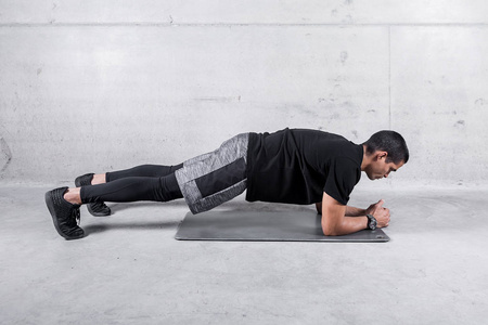 运动服运动员做腹部肌肉木板运动的侧视图