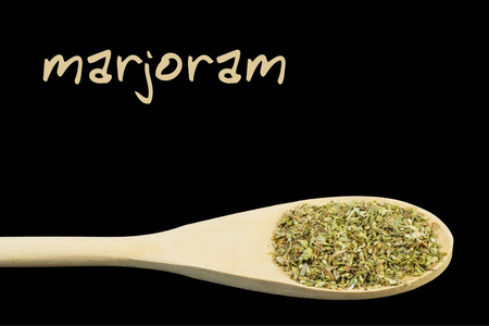 黑色背景的木勺上的marjoram