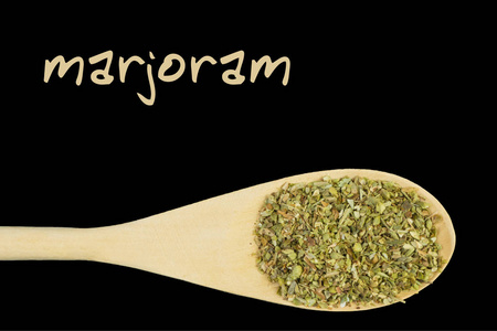 黑色背景的木勺上的marjoram