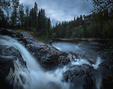 挪威北方北方北方森林的傍晚心情。 霍姆拉河上的瀑布。 长期曝光镜头。 自然光和颜色。