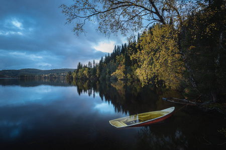 木船在湖边挪威美丽的秋天时光平静的水。 秋天风景中的旧船桨。