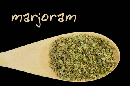 黑色背景的木勺上的marjoram