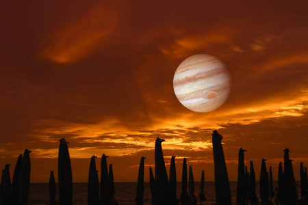 木星在天空和日落以及海滩伞的阴影。 折叠，因为夜晚是由美国宇航局提供的这幅图像的多风元素