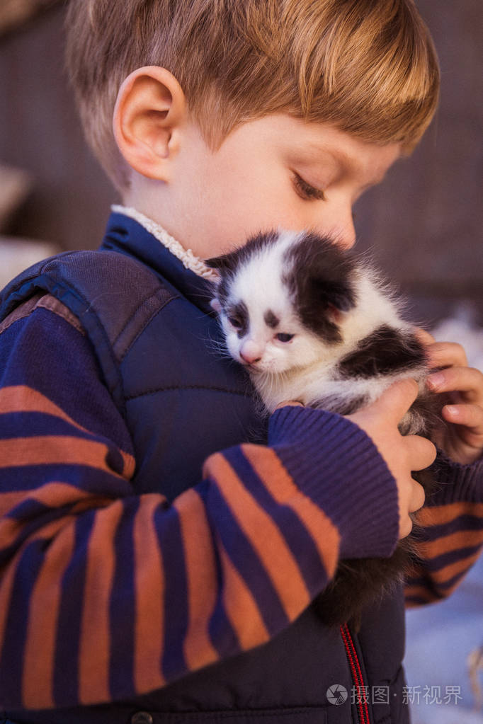 一个快乐的小男孩的他手里拿着一只小猫在户外