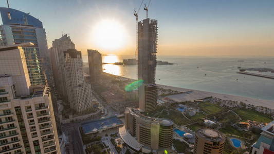 在迪拜阿联酋日落前，在Jumeirah海滩住宅J BR时间推移的现代摩天大楼和海滩的鸟瞰。 漂浮在海湾水上的船只和游艇