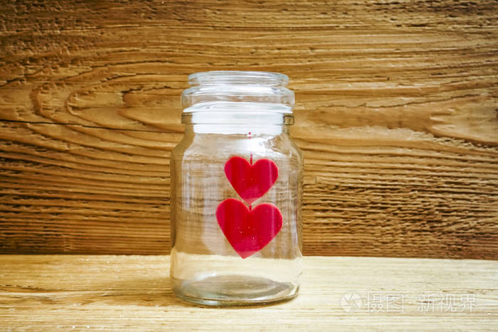 两颗红色的心挂在玻璃透明罐子里的螺纹上,里面有盖子. 情人节快乐