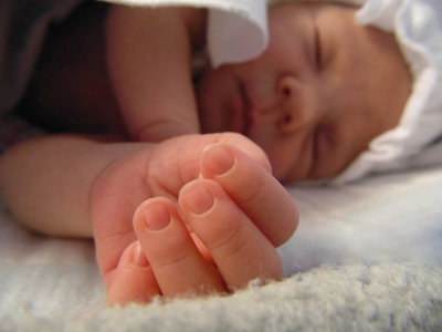 一个刚出生的小女婴睡得很香，用粉红色的小手指提出了她可爱的钢笔。