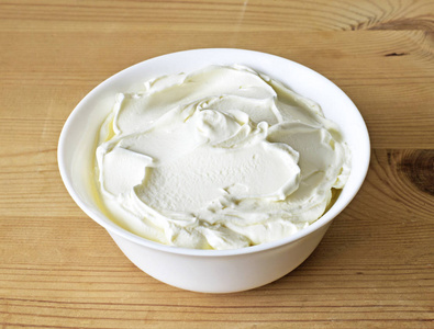 奶油奶酪夸克或酸奶在一个白色的碗。 乳制品健康饮食主题。 木制桌子背景。