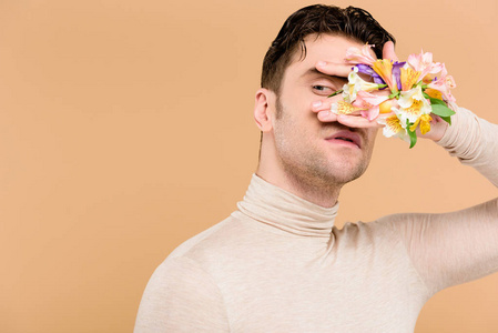 一个英俊的男人，手上拿着阿尔斯特美利亚的花，遮住了米色的脸