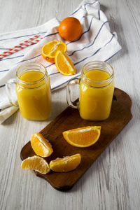 新鲜橙汁在玻璃瓶白色木制背景低角度视图。 特写镜头。