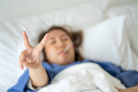 亚洲美女体温过低是通过发烧来测量的。 躺在床上进行身体康复。 医疗护理的概念，病人在家里自己。