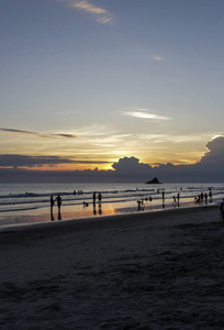 海滩上夕阳背景下人们的剪影