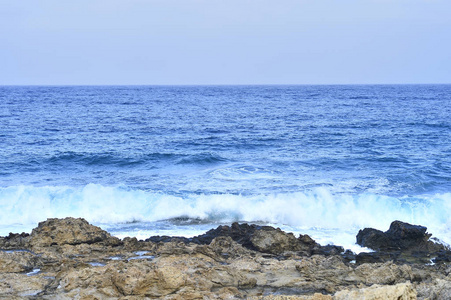 海岸海域。狂野的海滩。覆盖稀疏山地植被的天然岩层..夏天在岛上岩石海岸冲浪。