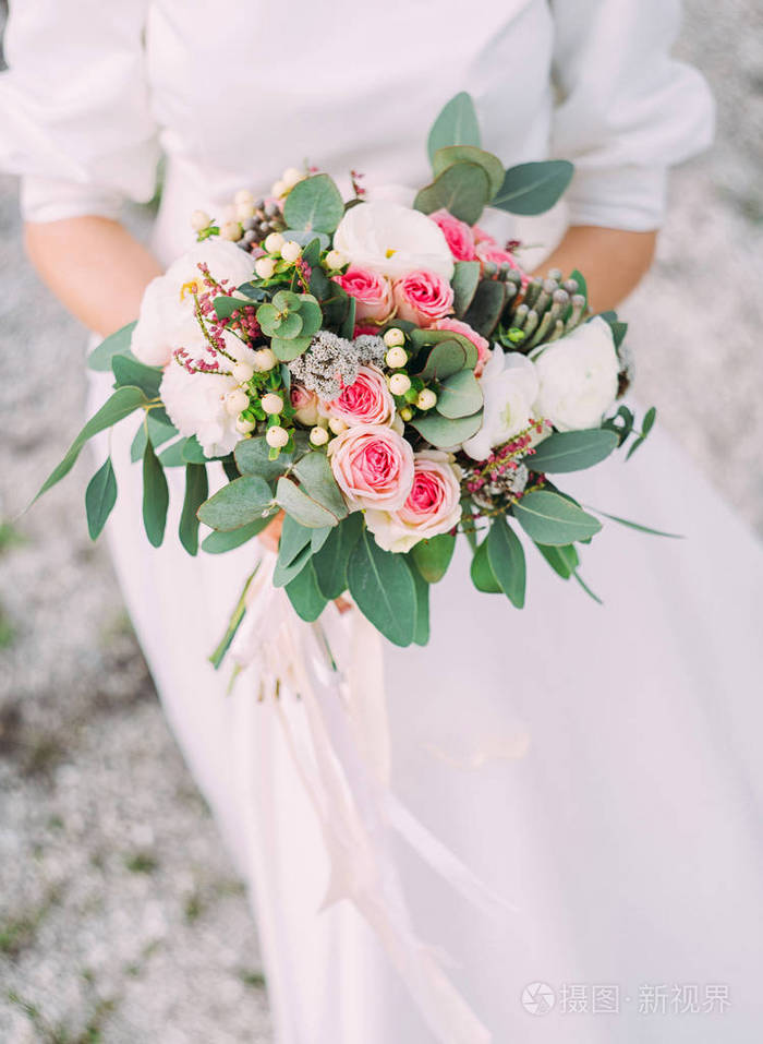 新娘身穿白色礼服,手捧婚礼花束,手捧红艳艳的鲜花