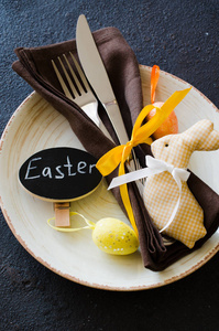 节日餐桌设置假日复活节晚餐在黑暗的桌子上。 装饰兔子和五颜六色的鸡蛋。 复制空间