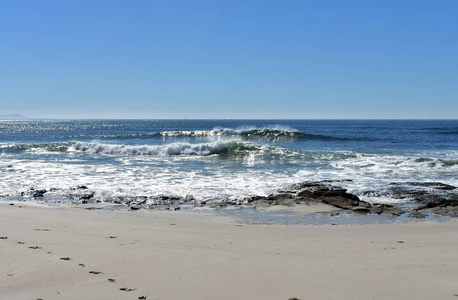 海滩上有岩石和小浪破碎。 蓝色的海洋与泡沫晴天。 加利西亚西班牙。
