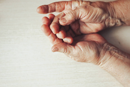 s hands resting on light background. Old lady sitting with her h