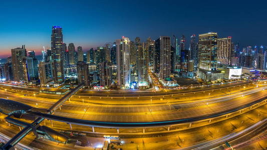 迪拜码头与交通谢赫扎耶德道路全景白天到晚上过渡时间灯打开。 阿联酋摩天大楼的夜间照明。 来自JLT的鸟瞰图