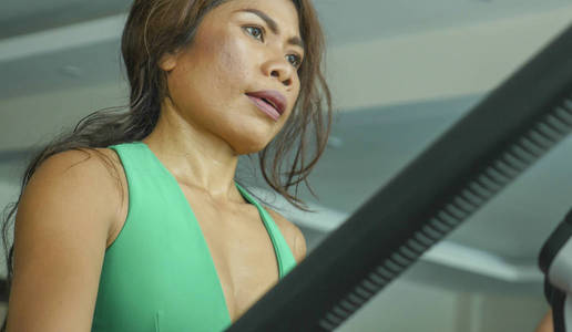 室内特写镜头年轻坚定专注的亚洲女性在健身房用椭圆机锻炼身体运动时汗流浃背疲惫不堪健康生活方式理念