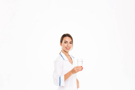 微笑着年轻的女医生穿着制服，被隔离在白色背景下，拿着杯子喝水