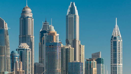迪拜码头摩天大楼日出时，从JLT在迪拜时间推移阿联酋的高空俯瞰。 现代塔楼，长长的阴影向下移动，交通在谢赫扎耶德的道路上。