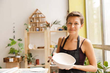 在车间制作陶瓷餐具的年轻妇女