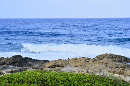 海边。 狂野的岩石海滩。 天然岩层覆盖着稀疏的山地植被。 夏天在岛上岩石海岸冲浪。