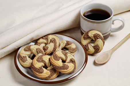 早餐在织物背景上的盘子和咖啡杯中的短饼干