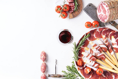 精选腌制肉类与格里西尼火腿萨拉米西红柿迷迭香和红酒在白色背面。 上面的风景。 复制空间