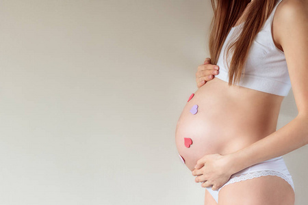 怀孕妇女的腹部7个月的特写，有粘合的心