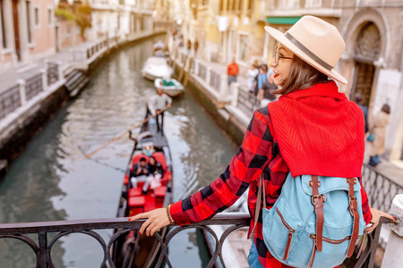 年轻快乐的亚洲旅行者女人在威尼斯一条狭窄的运河和街道的码头上。 意大利度假概念