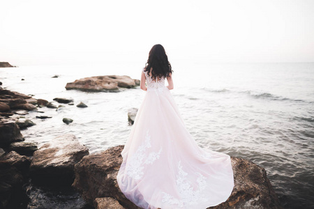 漂亮的女人，日落构成海边穿着婚纱的新娘