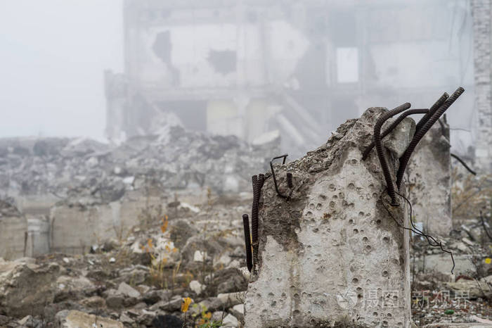 在雾蒙蒙的雾霾中,建筑物被摧毁的地基的残骸以桩和碎石的形式存在于