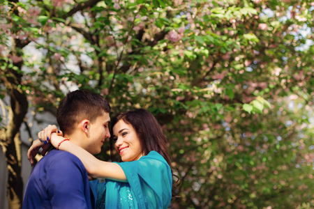 亲近一对相爱的夫妇，他们微笑着拥抱在日本樱桃旁边，带着鲜花