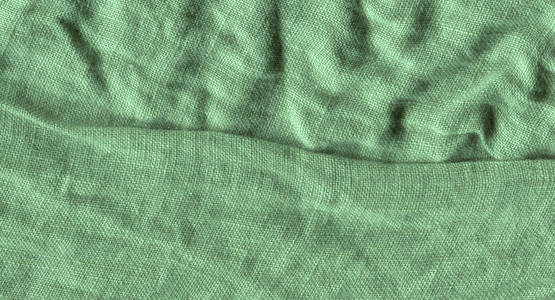 绿色亚麻纹理背景。 背景绿色织物表面