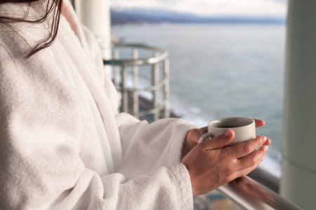 近距离观看美丽的女人豪华放松，手中拿着一杯咖啡茶在蓝天海上的酒店巴尔干半岛。 假期和放松的概念。