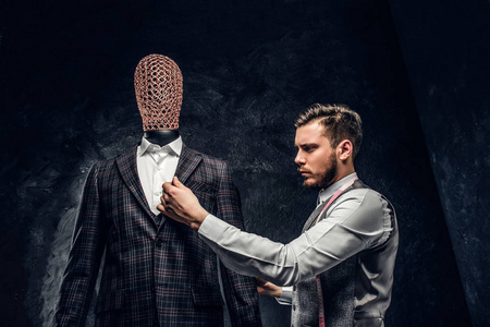 一位时装设计师在一个黑暗的裁缝工作室里检查定制的优雅男装的质量