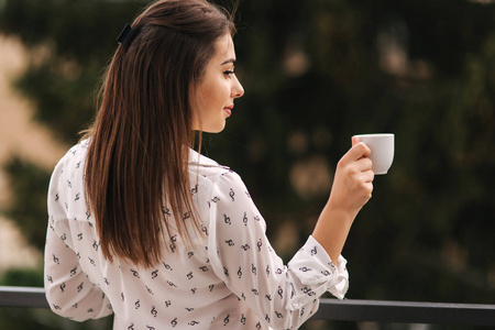 美丽的女孩拿着一杯咖啡。白衬衫。木背景