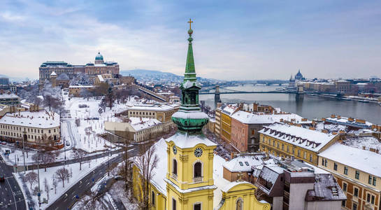 布达佩斯匈牙利天主教教堂与白雪覆盖的布达区布达城堡皇家宫殿瓦尔克特巴扎塞谢尼链桥和议会背景在一个下雪的冬天的早晨