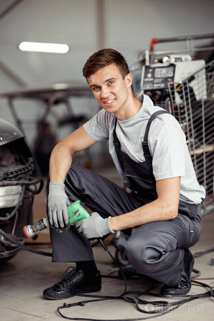 一位年轻而气立体的汽车修理工坐在一家汽车服务机构